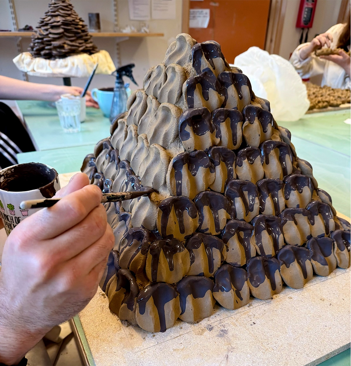 En keramikskulptur och hand som målar.